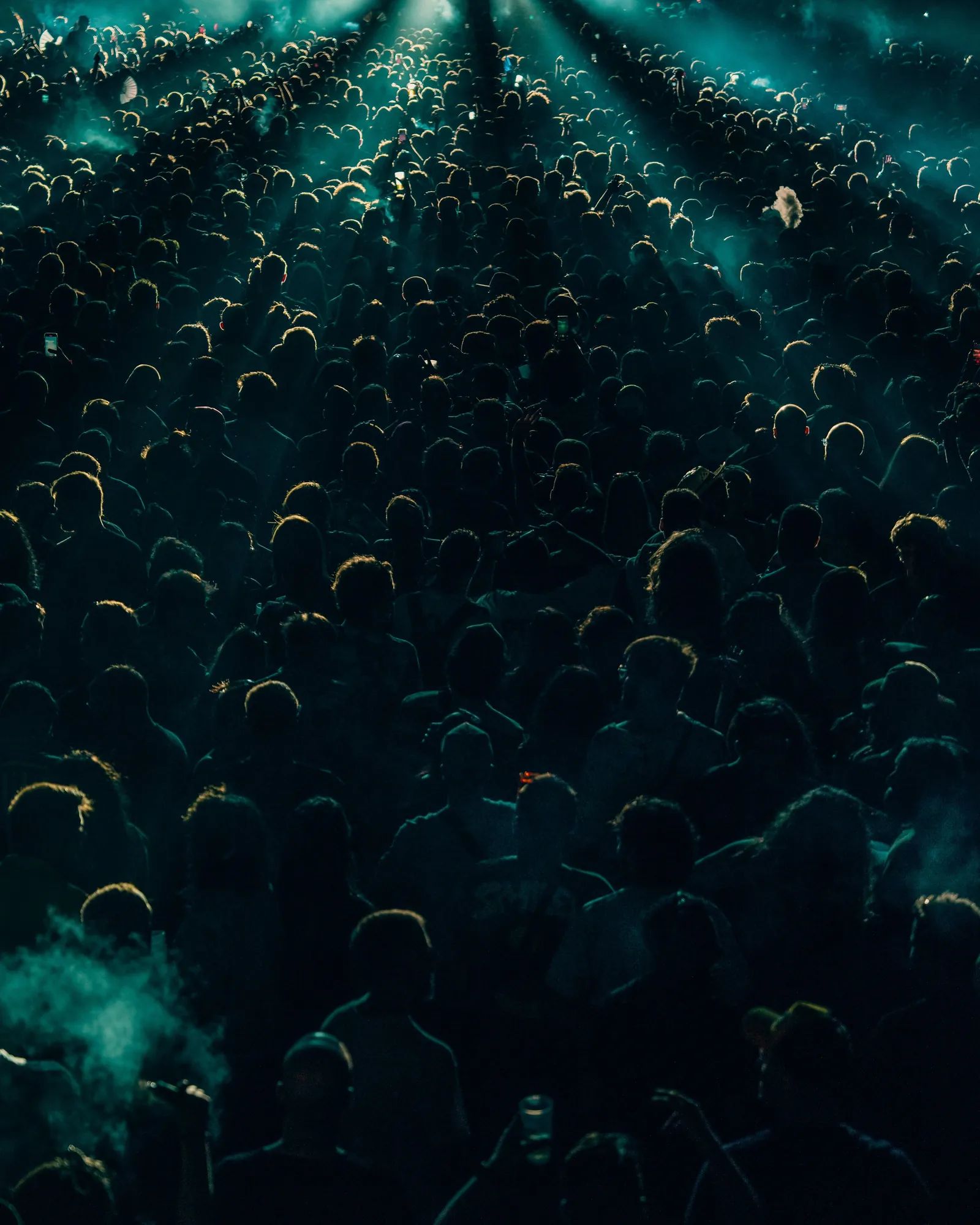 A dense concert crowd at night in teal light, seen from above, by Juan Actis