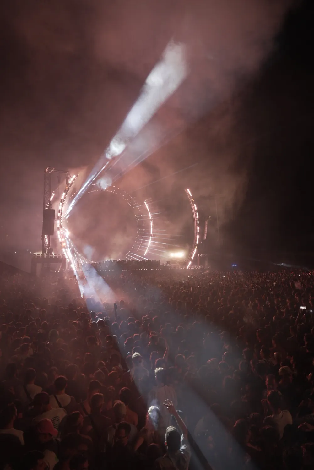 Unedited frame of the circular stage with a single beam over the crowd, tinted red and magenta