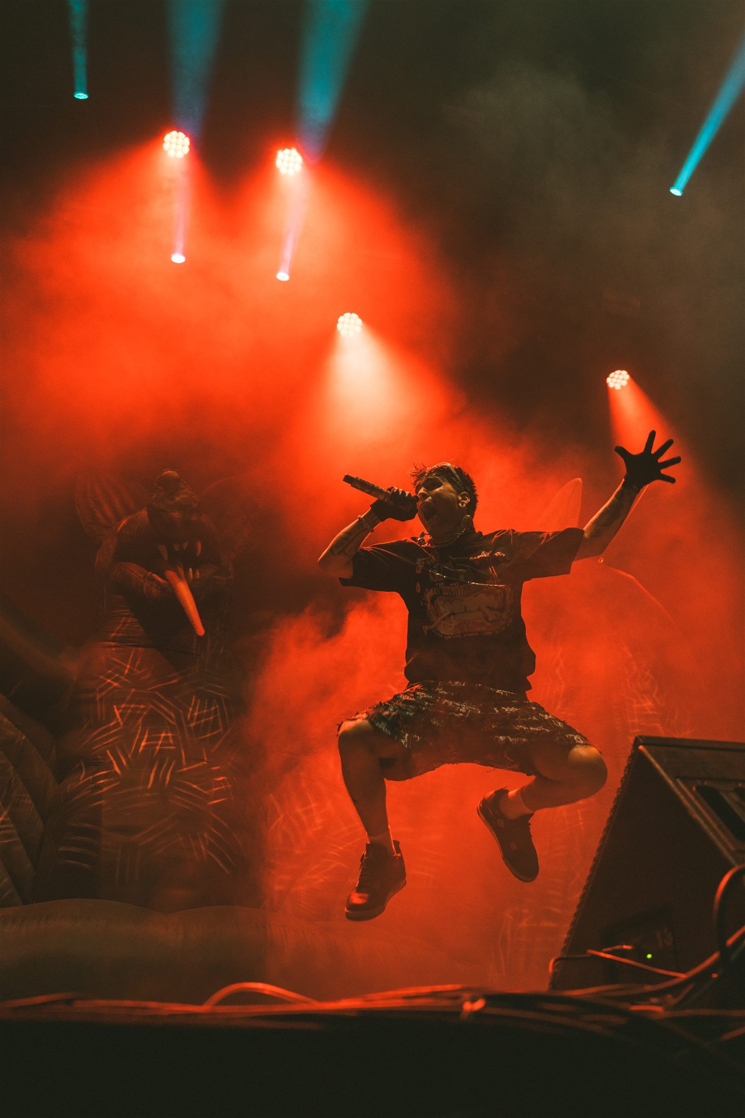Cantante saltando entre el humo rojo del escenario