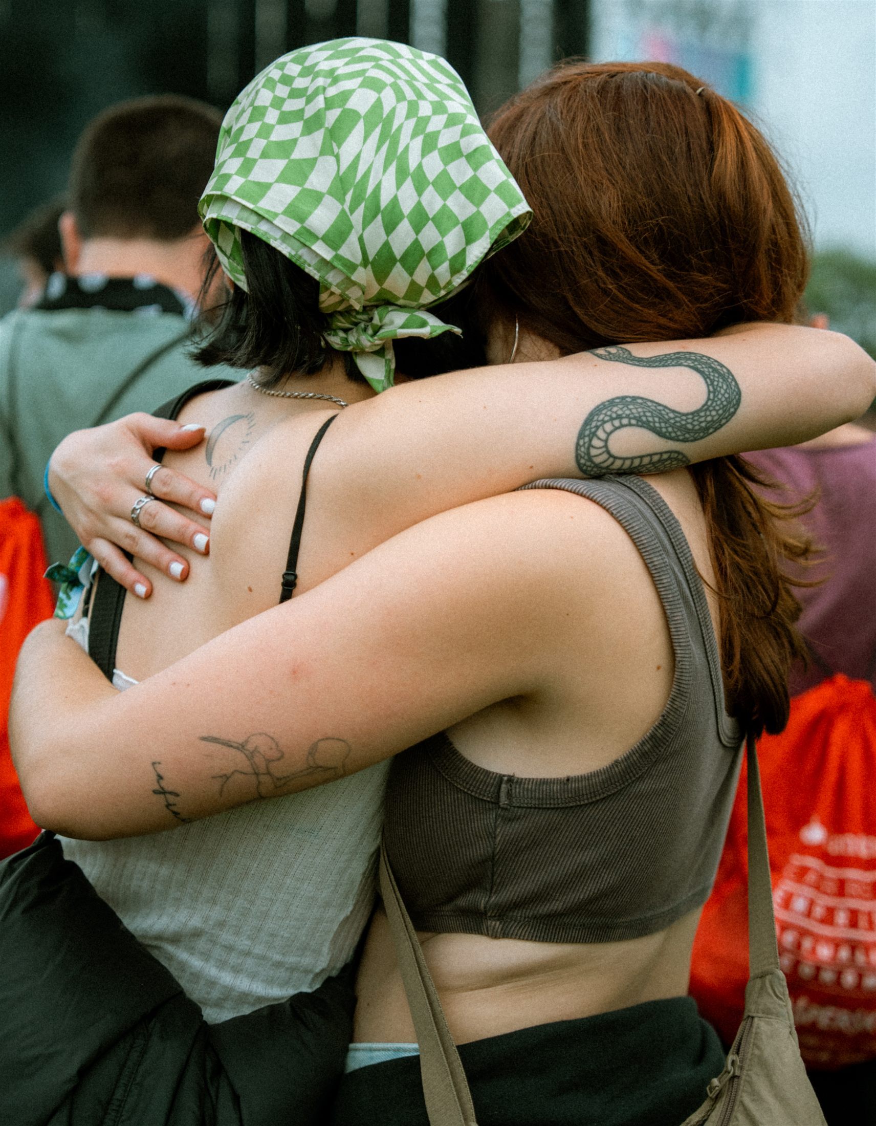 Dos amigas abrazadas de espaldas entre el público de un festival