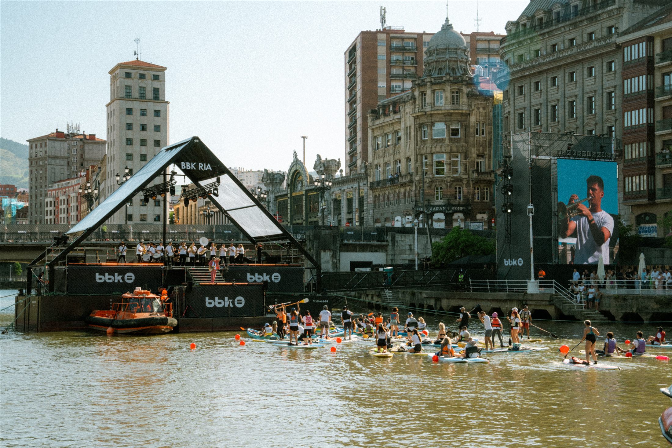 Público sobre tablas de paddle surf frente al escenario de BBK Ría